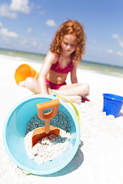 Girl digging in sand on beach