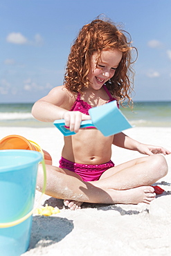 Girl digging in sand on beach