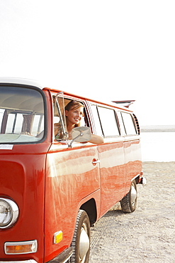 Teenage girl sitting in van on beach