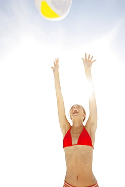 Young woman throwing beach ball in air