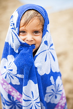 Baby girl (2-3) wrapped in towel on beach, Kauai, Hawaii