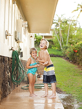 Children (2-3, 6-7) refreshing at outdoor shower, Kauai, Hawaii