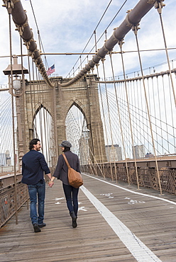 Couple holding hands and walking on Brooklyn Bridge, Brooklyn, New York