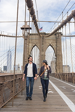 Couple holding hands and walking on Brooklyn Bridge, Brooklyn, New York