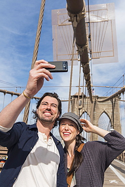 Happy couple taking selfie on Brooklyn Bridge, Brooklyn, New York