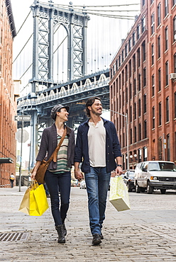 Couple walking on street, Brooklyn Bridge in background, Brooklyn, New York