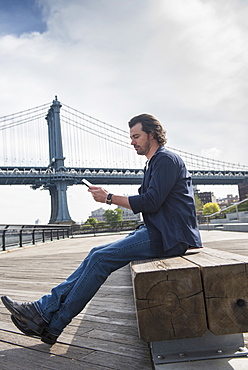 Man using tablet pc, Manhattan Bridge in background, Brooklyn, New York