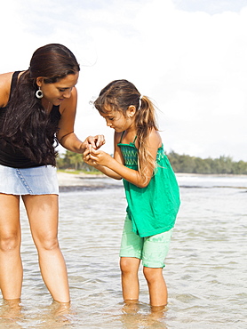 Girl (6-7) with mother walking in sea, Kauai, Hawaii