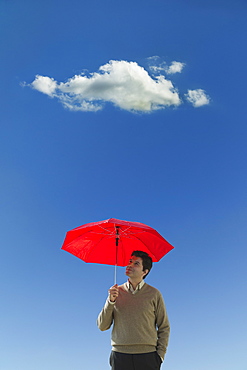 Man holding umbrella under cloud