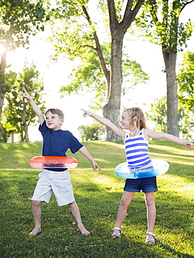 Two kids (4-5, 6-7) playing with inflatable rings in park, USA, Utah, Salt Lake City 