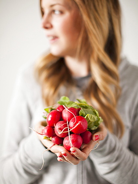 Portrait of attractive young woman holding radish