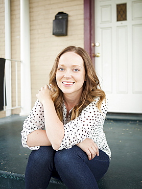 Portrait of happy young woman sitting on porch