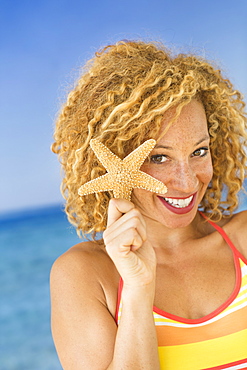 Portrait of young woman holding starfish