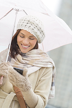 Woman with umbrella using phone