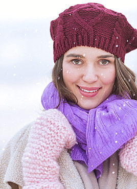 Portrait of young woman wearing knit hat, gloves and scarf