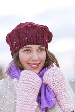 Portrait of young woman wearing knit hat, gloves and scarf