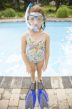 Girl in snorkeling gear standing at edge of swimming pool