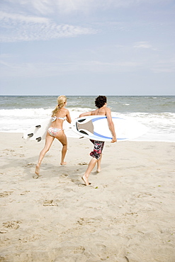 Couple running with surfboards