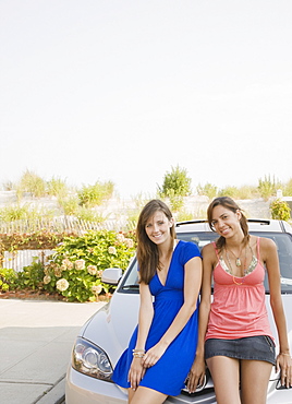 Young women sitting on car