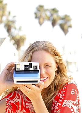 Woman taking photograph with instant camera