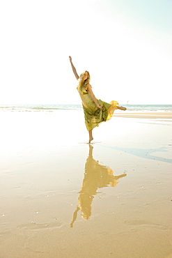 Woman standing on one foot at beach