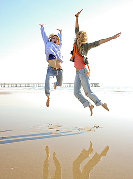 Two women jumping on beach