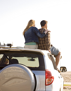 Couple sitting on top of car