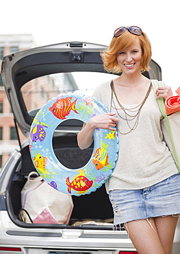 Portrait of young woman with beach gear in front of car