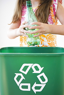 Close up of girl (6-7) throwing plastic bottle to recycling bin