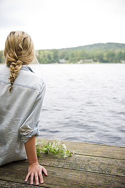 USA, New York, Putnam Valley, Roaring Brook Lake, Rear view of woman sitting on pier by lake