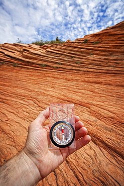 Human hand holding compass against eroded sandstone, Zion National Park, Utah