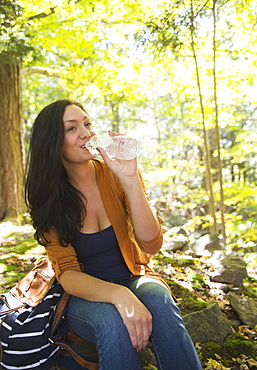 Woman drinking water in forest, Newtown, Connecticut