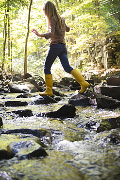 Woman walking on rocks in stream, Newtown, Connecticut