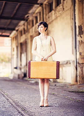 Woman in dress holding suitcase at train station, USA, New Jersey, Jersey City 