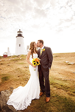 Portrait of married couple kissing, lighthouse in background, USA, Maine, Bristol 