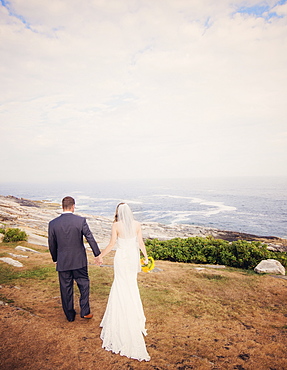 Rear view of married couple walking by sea, USA, Maine, Bristol 