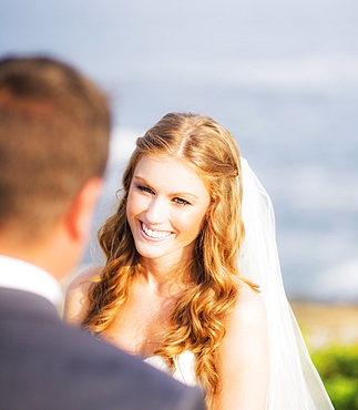 Groom looking at bride, sea in background