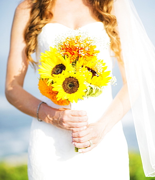 Mid section of bride holding sunflower bouquet