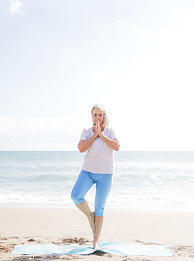 Senior woman practicing yoga on beach, Jupiter, Florida