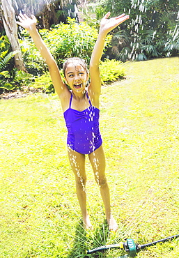 girl (8-9) playing in sprinkler