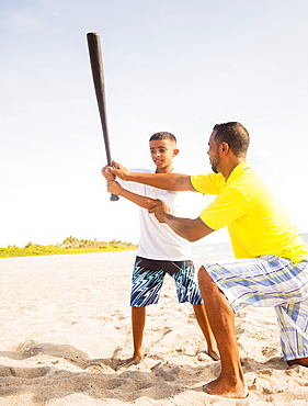 Father and son (10-11) playing baseball on beach, Jupiter, Florida