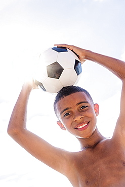 Boy (10-11) holding soccer ball on head