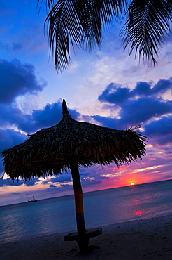 Aruba, silhouette of palapa on beach at sunset