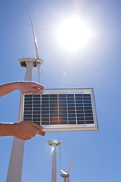 USA, California, Palm Springs, Woman's hands holding solar panel with wind turbines