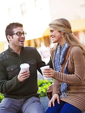 Young couple sitting with take-away coffee