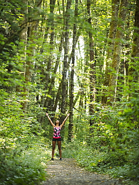 Young women with arms raised in forest, USA, Oregon, Portland