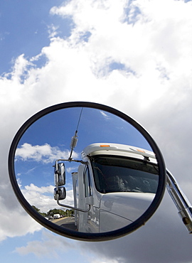 Reflection of semi-truck in side view mirror