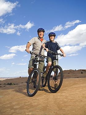 Portrait of father and son on mountain bikes