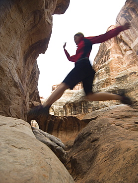 Woman jumping over rock formations