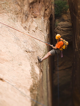 Man in rappelling gear at top of cliff